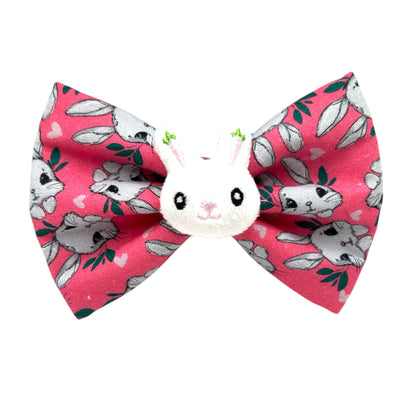 Pink Easter Pet bow tie. Grey rabbits all over the bow. With a plushy rabbit attached to the middle of the bow. 