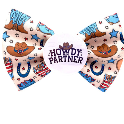 Cowboy themed bow tie. Light brown colour with cowboy hats, cowboy boots, USA themed. Howdy Partner badge in the centre