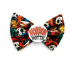 A Halloween dog bow tie featuring a vibrant Horror themed collage print with skulls, ghosts, and horror characters in orange, black, green, and white, secured with a central white circular pin that reads 'HORROR HOTTIE'.